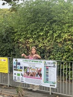 A girl beside an Ailsa's Aim charity banner
